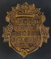 Odznak vydaný u příležitosti slavnostního otevření nové školní budovy české obecné školy v Chrastavě dne 18. listopadu 1923, NPMK.